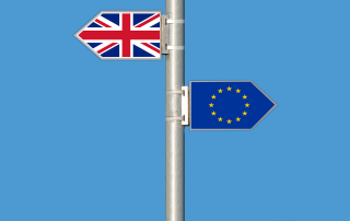 UK flag, EU flag pointing different directions for Brexit